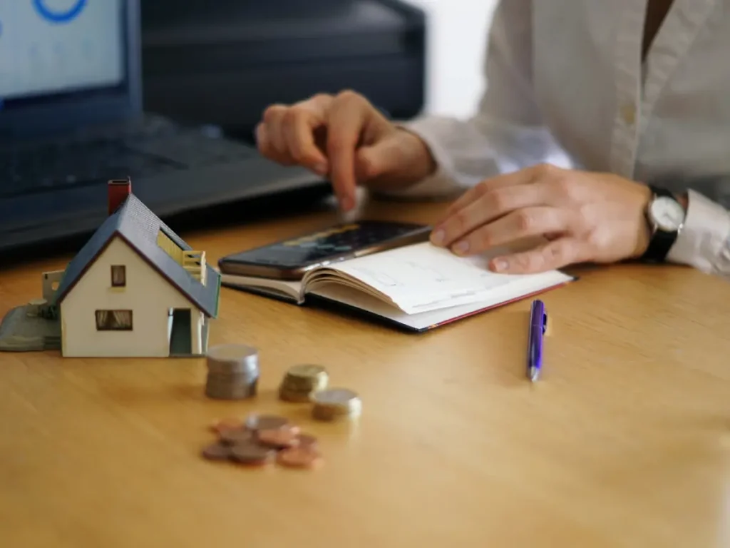 Homeowner calculating quarterly strata levies and property maintenance costs using a notebook and calculator.